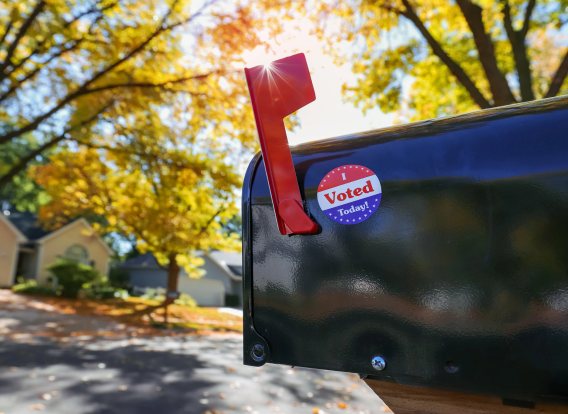 Vote by Mail Photo of a mailbox with a "vote" sticker on it.