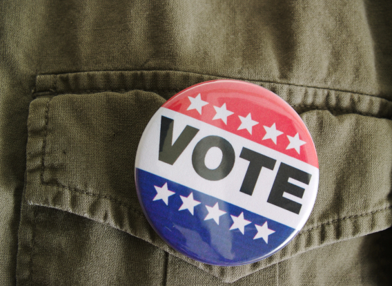 Image of a &quot;vote&quot; button on an Army green shirt.